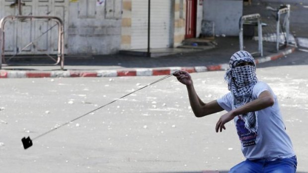 A Palestinian protester uses a slingshot to hurl a stone at Israeli troops during a demonstration in Hebron.