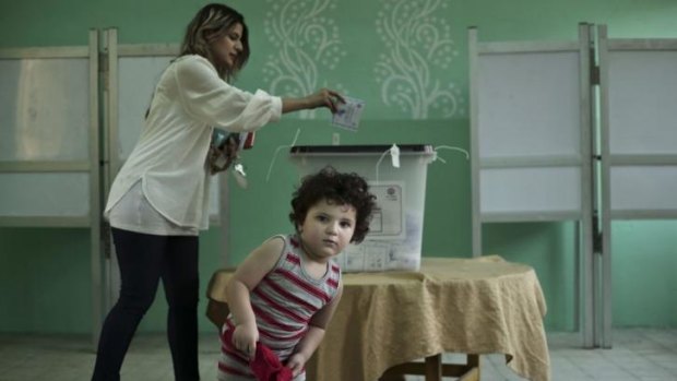 Low turnout ... An Egyptian voter casts her ballot in Cairo during the first day of the presidential election on Monday with a child in tow.