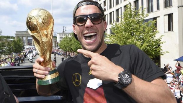 Germany's Lukas Podolski poses with the World Cup trophy during celebrations to mark the team's 2014 Brazil World Cup victory in Berlin.