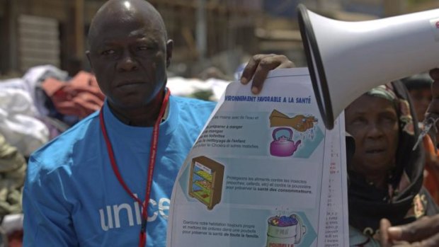 A UNICEF worker holds a poster bearing information to help prevent the spread of Ebola in Conakry.