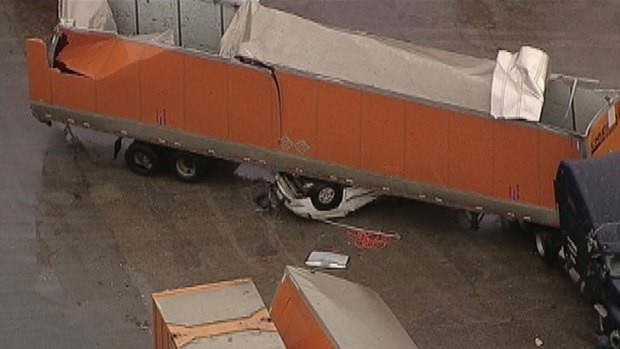 A car is crushed by a flying semi-trailer.