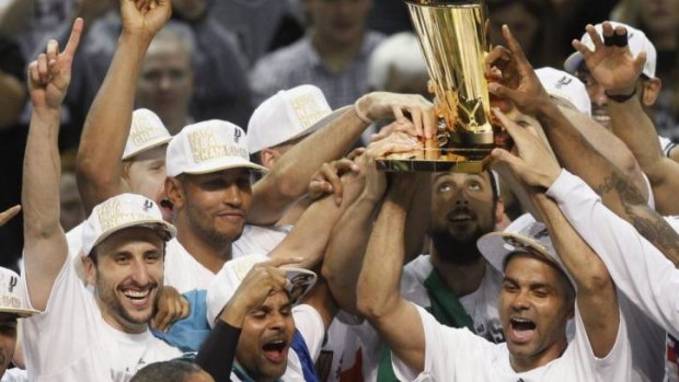The Spurs celebrate with the trophy.