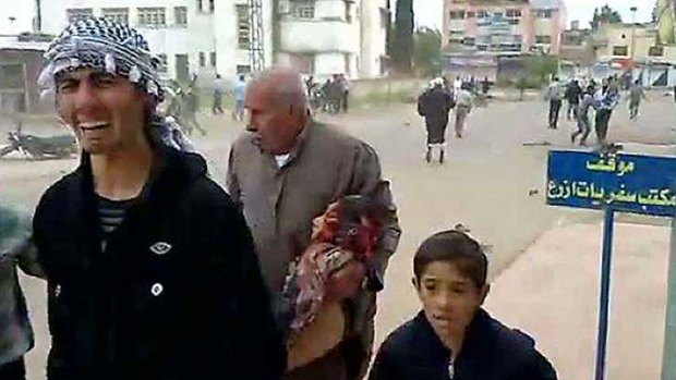 Anti-government protesters, including a man carrying a wounded boy, flee violence in southern Syria.