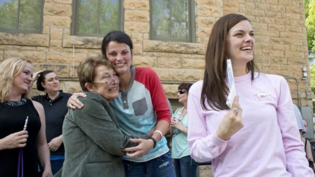 Jennifer Rambo, right, smiles as her partner Kristin Seaton, center, hugs the lead attorney who filed the Wright v. the State of Arkansas lawsuit.