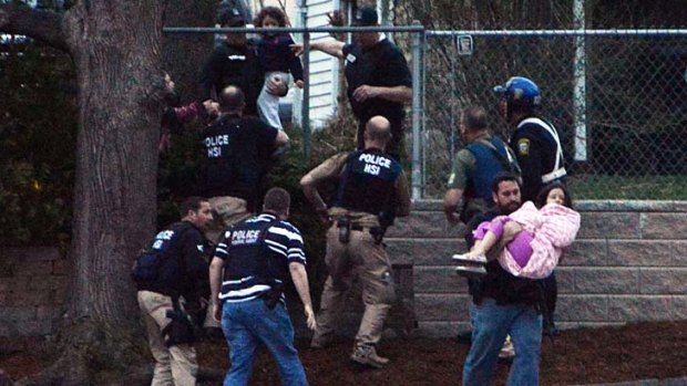 Fleeing the danger: an agent carries a child away from an area where one of the Boston bombing suspects was thought to be hiding.