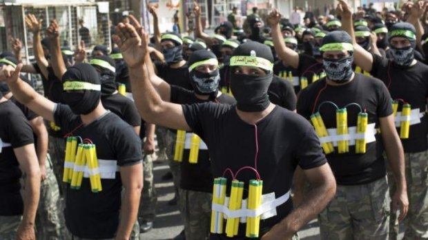Shiite militiamen wearing mock explosives march through the Sadr City neighbourhood of Baghdad in a show of force as Sunni jihadists fought Iraqi government troops in the north of the country.