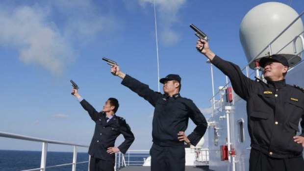 Display: Chinese personnel fire their pistols to signal the start of a naval exercise as they stand on a vessel on the East China Sea.