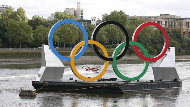 Giant Olympic rings mounted on a barge float on the River Thames yesterday.