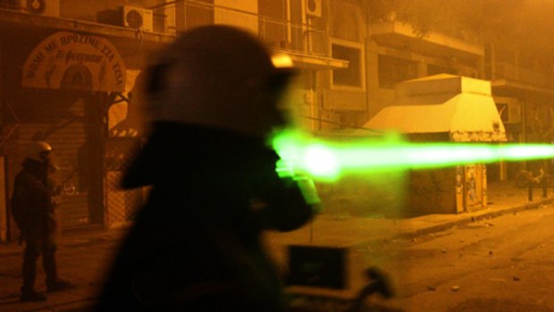 High-tech confrontation:  Protesters aim a laser pointer at riot police during clashes on the weekend in Athens  that followed  vigils for a youth killed eight days earlier by police.