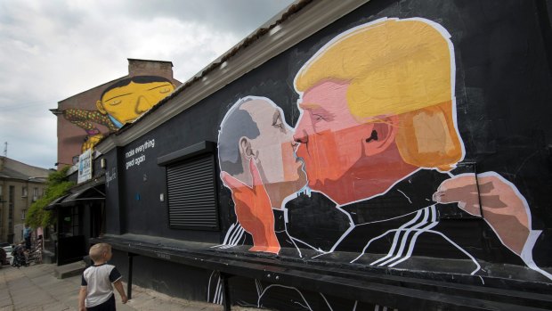 A child walks past a mural depicting Vladimir Putin and  Donald Trump in Vilnius, Lithuania.