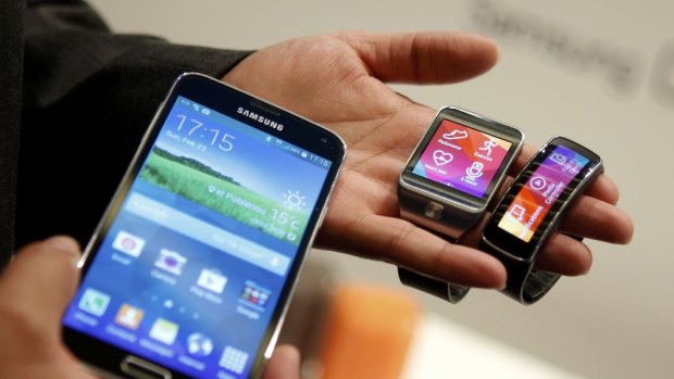 New Samsung Galaxy S5 smartphone (L), Gear 2 smartwatch (C) and Gear Fit fitness band. Salesforce wants to facilitate the adoption of the smartwatch and other wearable devices in business.