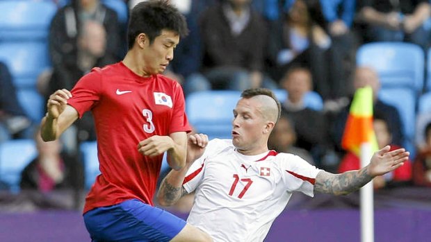 South Korea's Yun Suk-young (left) fights for the ball with Switzerland's Michel Morganella during their group match at the London Olympics.