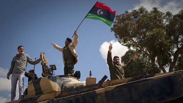 Libyan rebels celebrate on a captured tank  near Benghazi after the coalition air strike that left many government vehicles in pieces.