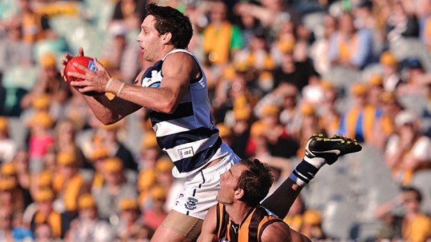Geelong's Harry Taylor leaps to mark over Hawthorn defender Cameron Bruce.