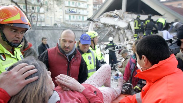 An injured woman is carried from the rubble in the town of L'Aquila (left), as firefighters search for survivors in the debris.