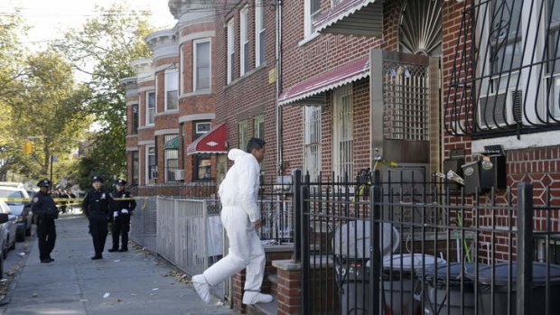 A crime scene detective walks up the steps at the scene of a multiple fatal stabbing in the Sunset Park neighborhood of Brooklyn, in New York.