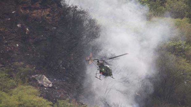 A Pakistani Army helicopter hovers over the crash site.