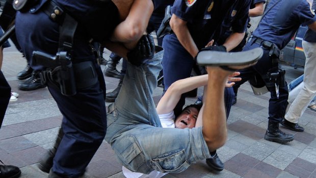 Police officers detain an protester while police try to dismantle a demonstration at Puerta del Sol Square in Madrid.