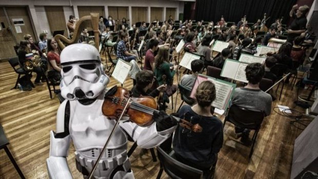 Youth orchestra manager Michelle Forbes as a Star Wars Storm Trooper with conductor Brett Kelly and the 85-strong orchestra.