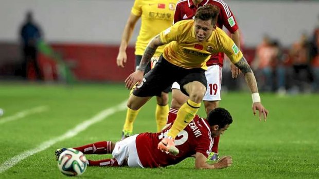 Zhang Linpeng of China's Guangzhou Evergrande jumps over Ahmed Kenawi of Egypt's Al Ahly.