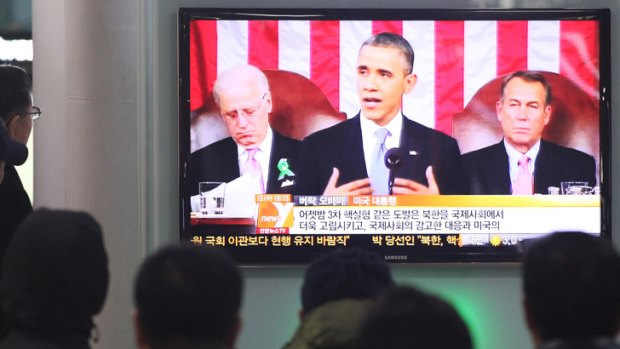 People watch a television news report on U.S. President Barack Obama's State of the Union address at Seoul Railway Station in Seoul, South Korea.