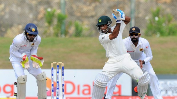 Pakistan's Asad Shafiq forces the ball to the cover region as Sri Lanka's wicketkeeper Dinesh Chandimal looks on.