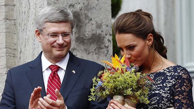 Catherine, Duchess of Cambridge, smells a bouquet of flowers as Canada's Prime Ministers Stephen Harper looks on.