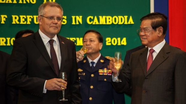 Australian Immigration Minister Scott Morrison and Cambodian Interior Minister Sar Kheng hold a flute of champagne after signing a deal to resettle refugees from Australia to Cambodia.