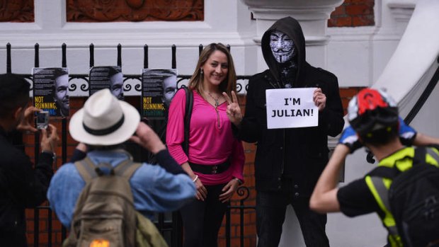 A protester in a Guy Fawkes mask attracts attention outside the Ecuadorean embassy in London, where the Wikileaks founder has sought political asylum.