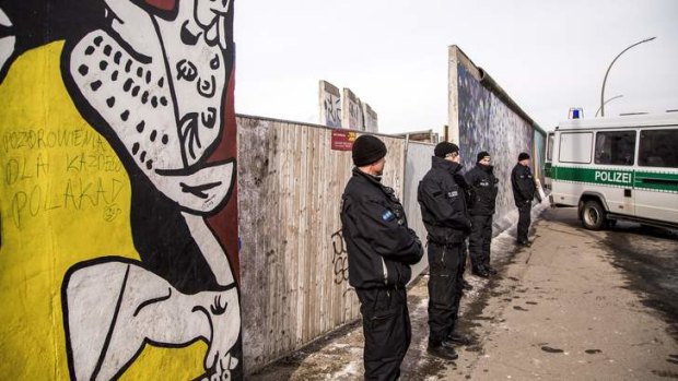 Policemen stand guard next to a section of the Berlin Wall which has been removed to make way for a luxury apartments development.