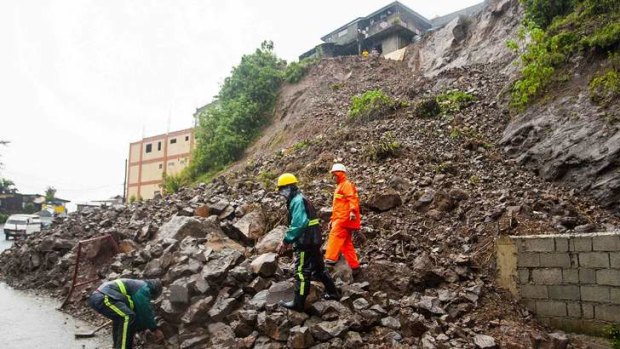 Government workers clear debris from a road following a landslide that occurred at the height of Typhoon Utor in Baguio city, in northern Philippines, August 12, 2013. The most powerful typhoon to hit the Philippines this year triggered landslides and floods on Monday, disrupting power and communication links to leave one man dead and 13 fishermen missing, weather and disaster officials said.