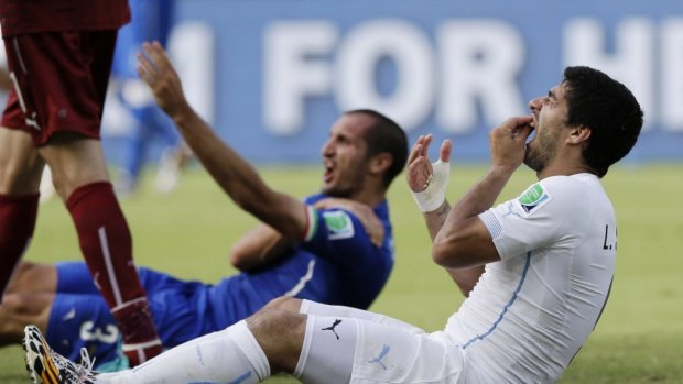 Luis Suarez holds his mouth as Giorgio Chiellini protests in the background.
