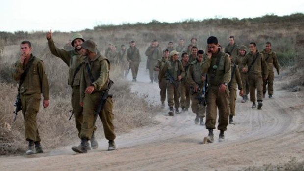 Israeli soldiers walk on a dirt road next to an army deployment near the border between Israel and the Hamas-controlled Gaza Strip on July 25.