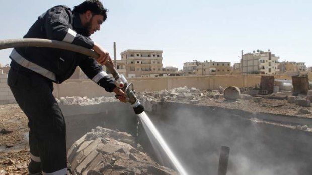 A firefighter hoses water on a burning gas station, which activists say was the result of shelling by forces loyal to Syria's President Bashar al-Assad in Raqqa province on Friday.