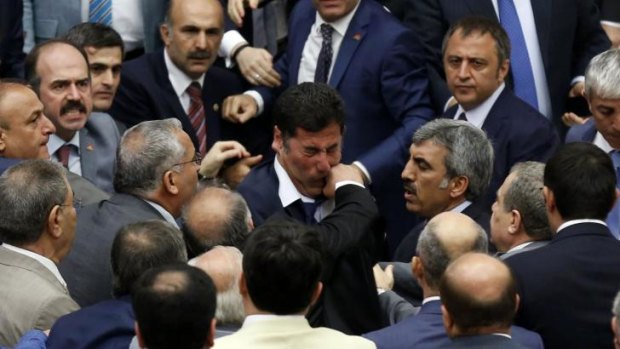 Tense times: an MP from Mr Erdogan's ruling AKP punches an opposition MP during a debate on the wars in neighbouring Iraq and Syria on August 4.