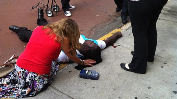 Crossfire &#8230; a passer-by tends the shooting victim Robert Asika outside the Empire State Building.