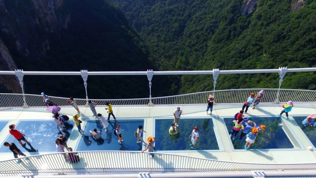 Visitors walk across a glass-floor suspension bridge in Zhangjiajie in southern China's Hunan Province.