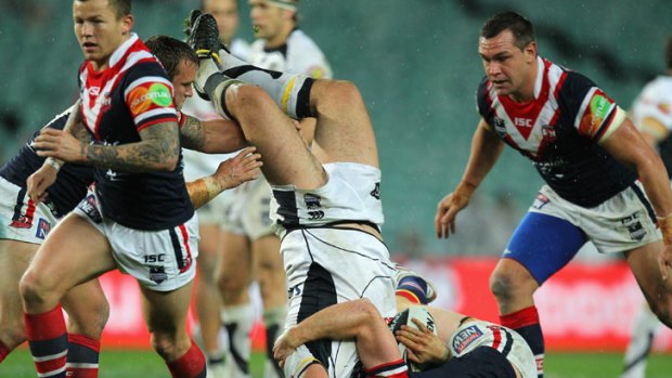 Russell Packer of the Warriors is tackled by the Roosters' defence.