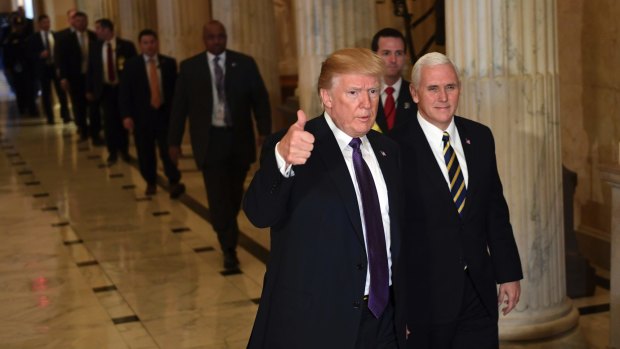 President Donald Trump gives a thumbs up as he walks with Vice-President Mike Pence as he leaves Capitol Hill in Washington on  Thursday