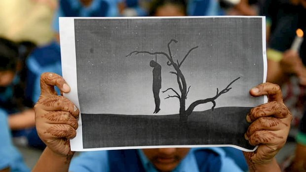 An Indian schoolgirl holds a placard with an image of a hanging man during a rally in Ahmedabad.