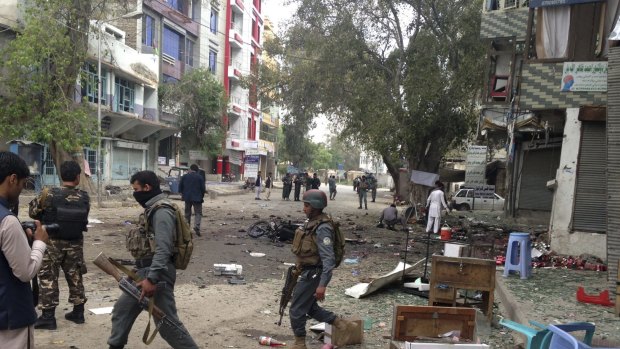 Afghan security forces members inspect the site of a suicide attack near a new Kabul Bank in Jalalabad, Afghanistan, on Saturday, April, 18, 2015, in which at least 33 people were killed. 