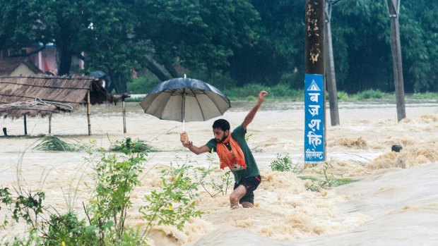 A Nepalese man looses his balance while crossing a flooded street in Birgunj, Nepal, on Sunday.