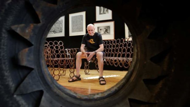 Murray Walker sits on the bench made from horseshoes, framed through a tyre flower.