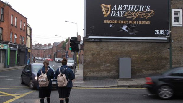 Morning commuters pass a billboard advertising Arthur's Day in Dublin, Ireland.