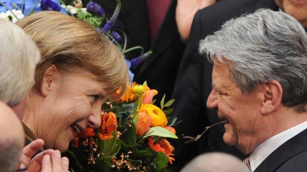 Blooming freedom &#8230; the German Chancellor, Angela Merkel, hands a bouquet to the new President, Joachim Gauck, on Sunday.
