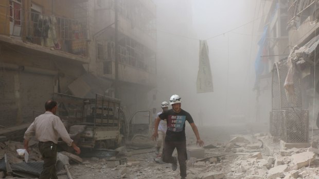 Search and rescue team members run around the debris of damaged buildings after Assad forces and Russian army carried out airstrikes.