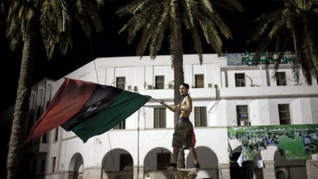 A rebel fighter signals his defiance and victory by waving a pre-Gaddafi  flag in the heart of the capital, Tripoli.