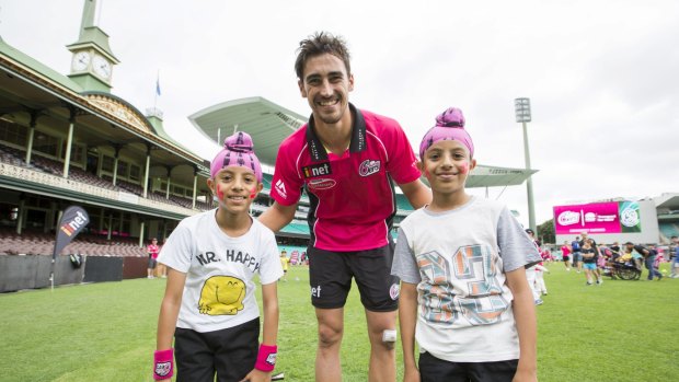 All smiles: Mitchell Starc with twins Arsh (left) and Karan Girn, 9, of Earlwood at the Sydney Sixers fan day on Sunday.