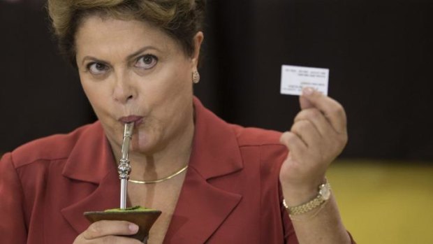 Brazil's President and Workers Party presidential candidate Dilma Rousseff shows her electronic voting receipt as she drinks a herbal tea called "mate".