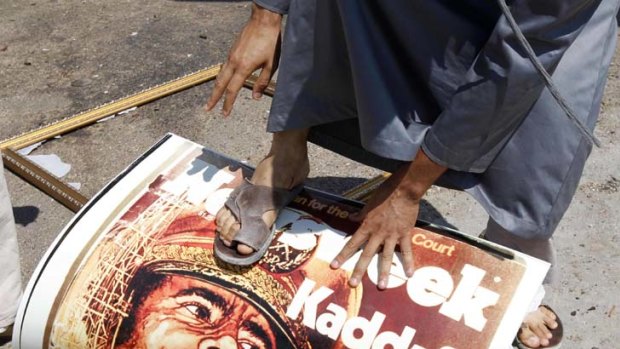 A man steps on a poster of Libya's leader Muammar Gaddafi.